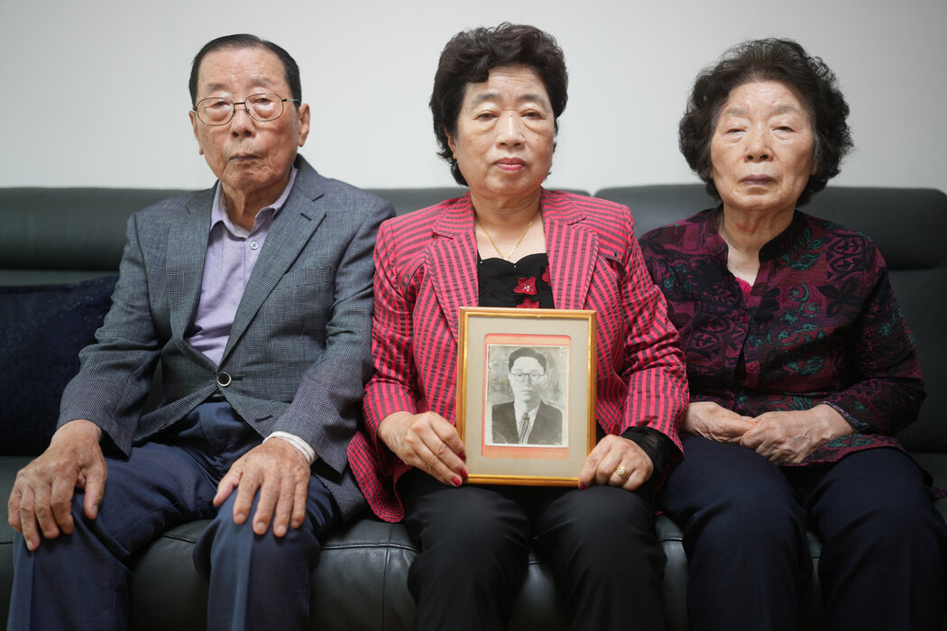 崔秉熙手里拿着被朝鲜绑架的父亲的唯一照片。6月，她和她的伯父和姑妈（即父亲的兄弟姐妹）——86岁的崔车文（左）和79岁的崔泰鹏——坐在一起。