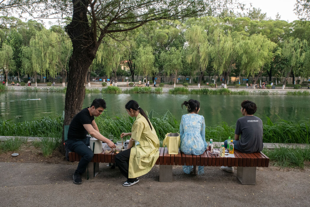 人们在亮马河边野餐。一些人抱怨说，在公园里游泳的人“有碍观瞻”，影响别人拍照。